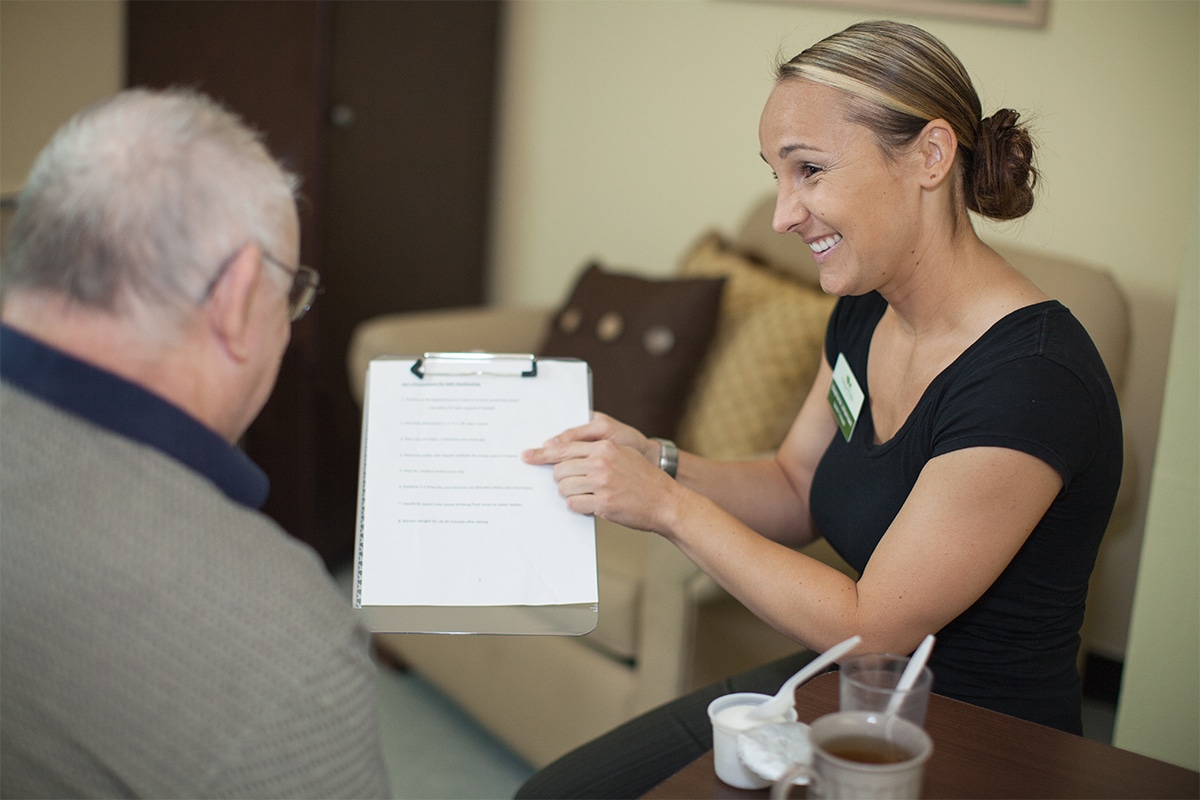 PACS-300x200-pain1 auburn oaks female staff member pointing to a clipboard and showing elderly old man