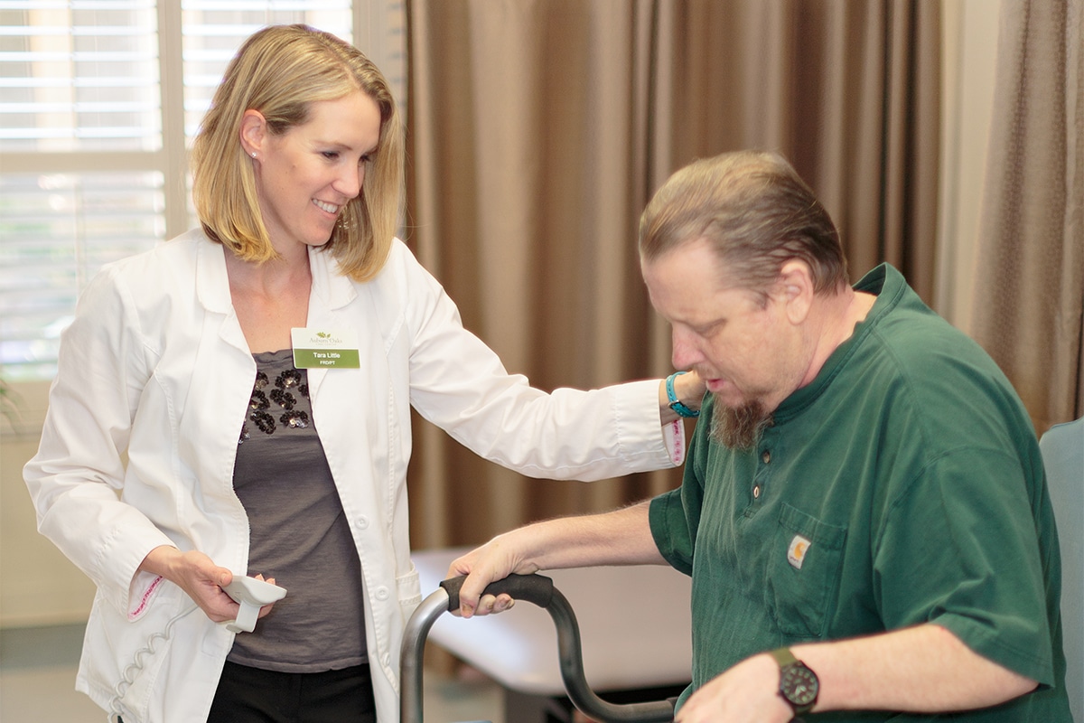 nurse in white coat helping man in walker