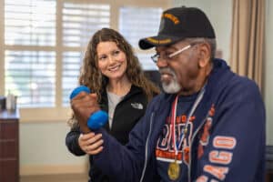 auburn oaks female staff member helping elderly man lift weights
