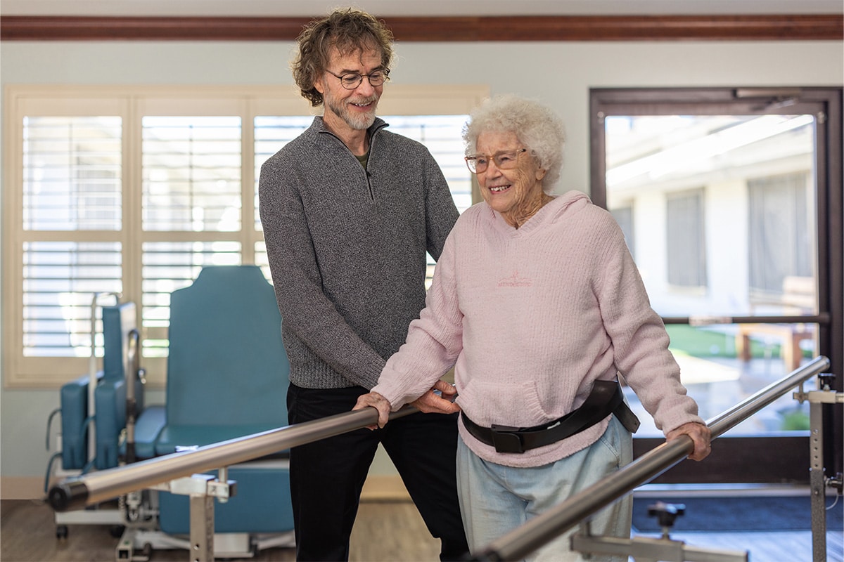 PACS-300x200-rehab2 auburn oaks male staff member assisting elderly woman in walking with support belt and railings