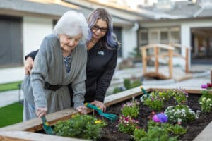 nurse and elderly woman gardening at auburn oaks