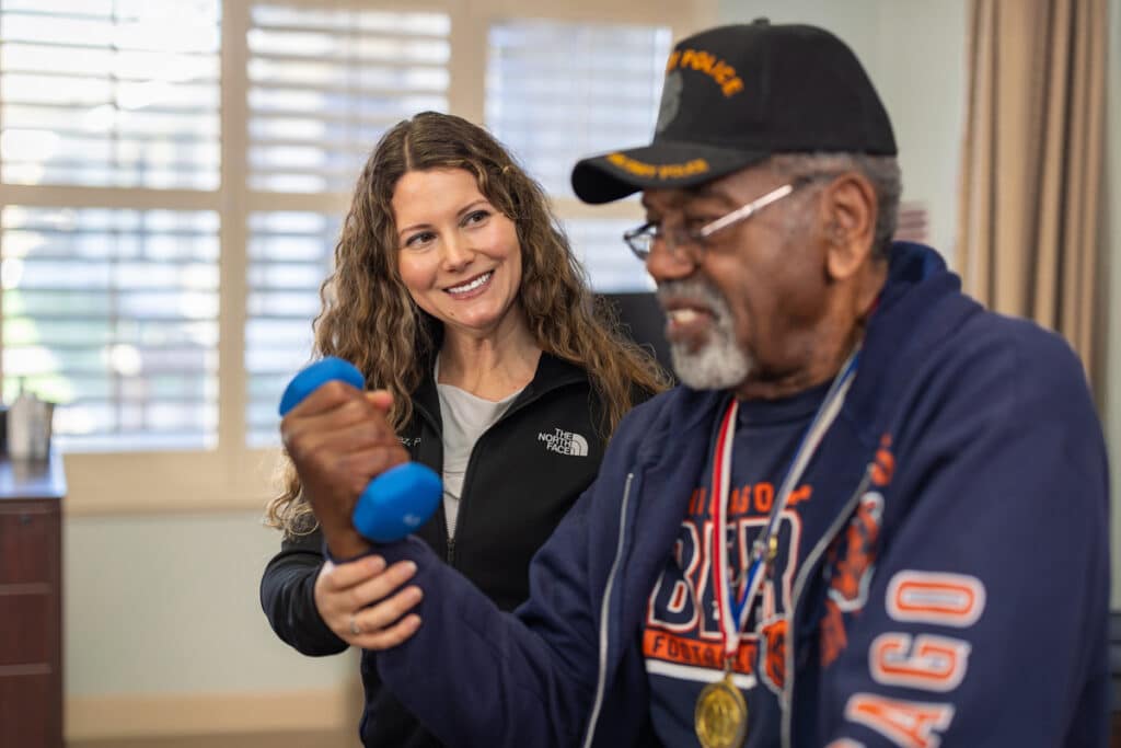 nurse assisting elderly man with lifting weights at auburn oaks care center